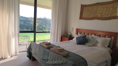 1 dormitorio con 1 cama con toallas en Kaka Lodge at Kotare House en Tawharanui