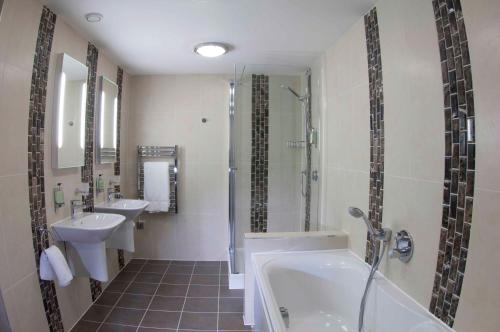 a bathroom with two sinks and a tub and a shower at The Lodge at Prince's in Sandwich