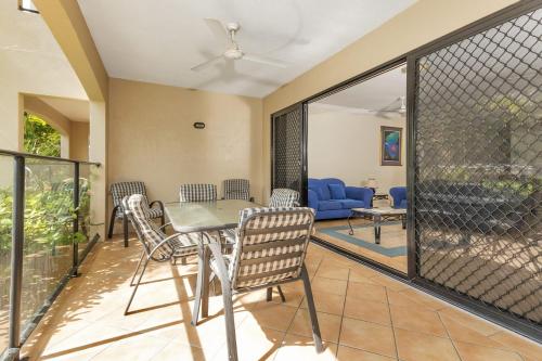 a screened in porch with a table and chairs at Mediterranean Beachfront Apartments in Yorkeys Knob