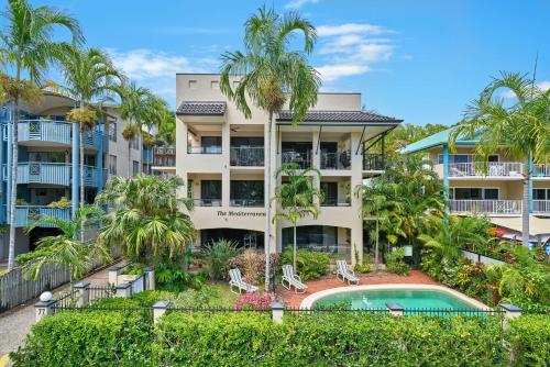 um edifício de apartamentos com piscina e palmeiras em Mediterranean Beachfront Apartments em Yorkeys Knob