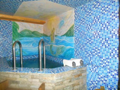 a blue tiled bathroom with two sinks and a mural at GALIRAD Hotel in Ustʼ-Kamenogorsk