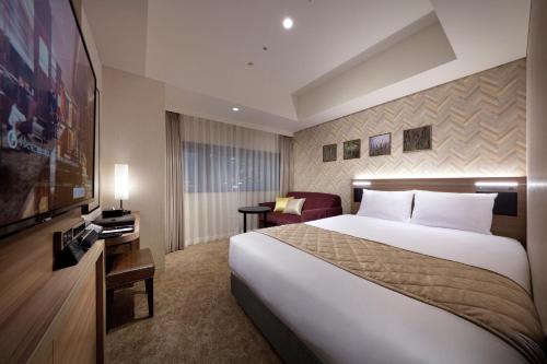 a hotel room with a large bed and a chair at Villa Fontaine Grand Tokyo Ariake in Tokyo
