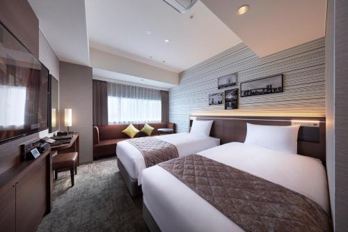 a hotel room with two beds and a couch at Villa Fontaine Grand Tokyo Ariake in Tokyo