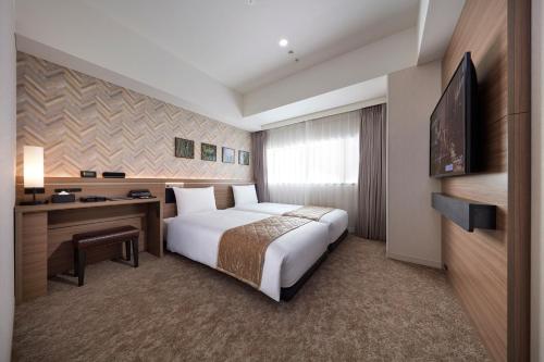 a hotel room with a bed and a desk and a television at Villa Fontaine Grand Tokyo Ariake in Tokyo