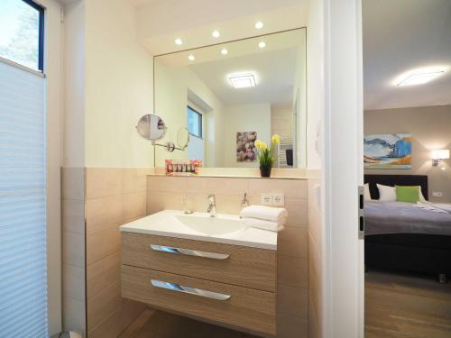 a bathroom with a sink and a mirror and a bed at Terrassenwohnung "Treibholz" - Oase am Haff in Garz-Usedom