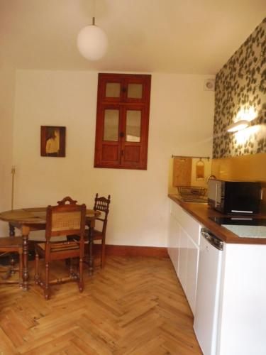 - une cuisine et une salle à manger avec une table et un four micro-ondes dans l'établissement Charmant appartement sur cour, Le Berlingott, à Bagnères-de-Bigorre