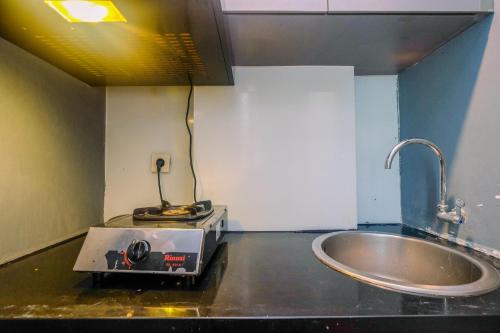 a small kitchen with a sink and a stove at Modern Furnished @ 1BR Margonda Residence 1 Apartment By Travelio in Depok