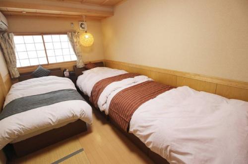 2 camas en un dormitorio con ventana en Yadokari Osaka en Neyagawa