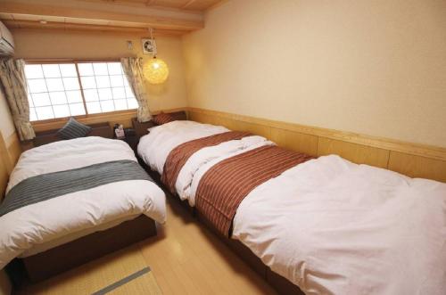 two beds in a bedroom with a window at Yadokari Osaka in Neyagawa