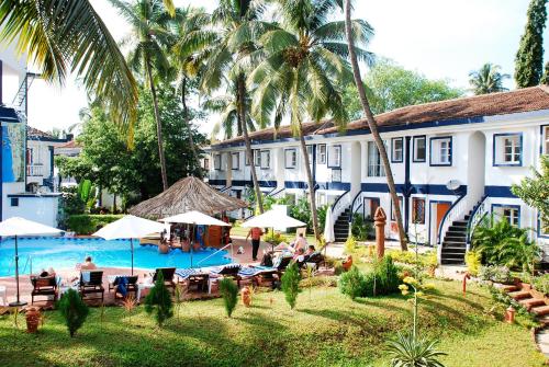a hotel with a swimming pool and people sitting around it at Santana Beach Resort in Candolim