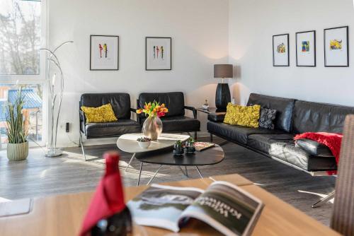 a living room with a black couch and a table at Appartement "Kliffkante" mit Penthouseflair - Oase am Haff in Garz-Usedom