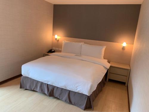 a bedroom with a large bed with white sheets and pillows at HATAGO+ THE ALLEY in Taipei