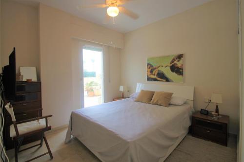 1 dormitorio con cama blanca y ventana en Apartamento CasaTuris enfrente al mar en Playa Muchavista C102, en El Campello