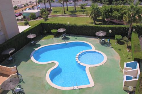 una vista aérea de una piscina con sombrillas en Apartamento CasaTuris enfrente al mar en Playa Muchavista C102, en El Campello