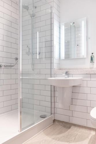 a white bathroom with a sink and a shower at The Merlin by Innkeeper's Collection in Alderley Edge