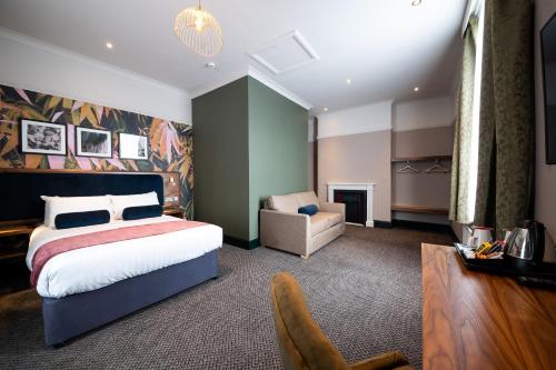 a hotel room with a bed and a chair at The Merlin by Innkeeper's Collection in Alderley Edge
