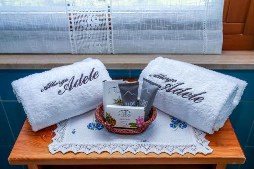 a table with two white towels and a basket of flowers at Albergo Adele in Bormio