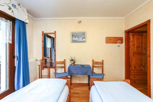 a bedroom with two beds and a table at Albergo Adele in Bormio