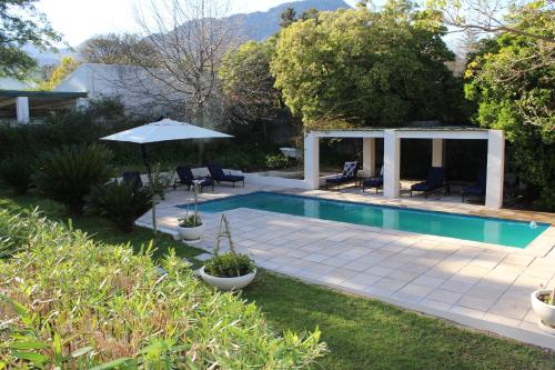 a pool with chairs and an umbrella in a yard at Residence Vive la Vie in Franschhoek