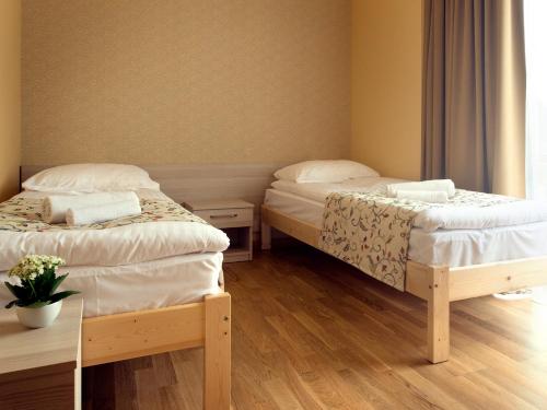 two beds in a small room with wooden floors at Kamanos in Utena