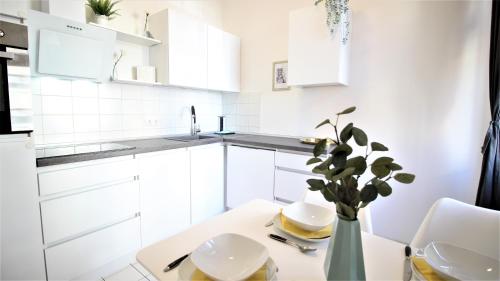 una cocina blanca con una mesa y un jarrón con una planta en Wohnen am Main - gemütlicher Altbau, zentral en Würzburg