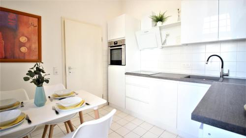 a kitchen with white cabinets and a table with chairs at Wohnen am Main - gemütlicher Altbau, zentral in Würzburg