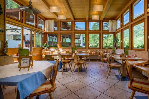 Un restaurante con mesas y sillas en una habitación con ventanas. en Hotel Restaurant Rosmarie, en Pfelders