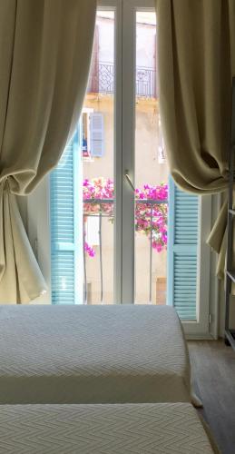 a bedroom with a bed and a large window at Hotel Cyrnos in Cargèse