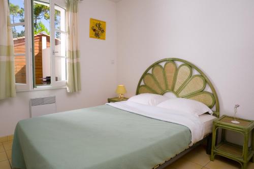 a bedroom with a large bed with a green headboard at Madame Vacances les Mas de Saint Hilaire in Saint-Hilaire-de-Riez