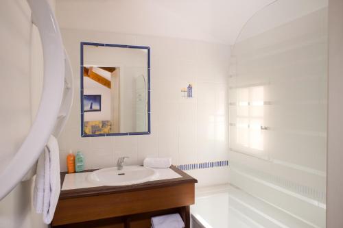 een witte badkamer met een wastafel en een spiegel bij Madame Vacances les Mas de Saint Hilaire in Saint-Hilaire-de-Riez