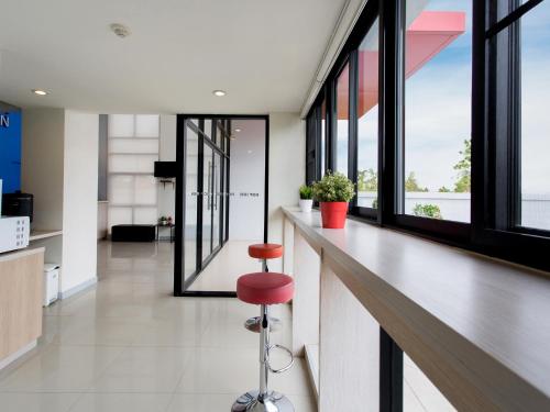 a bar with a red stool in a room with windows at HOP INN Chiang Mai Airport in Chiang Mai