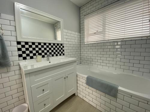 uma casa de banho com um lavatório, uma banheira e um espelho. em Net Hier em Eersterivierstrand
