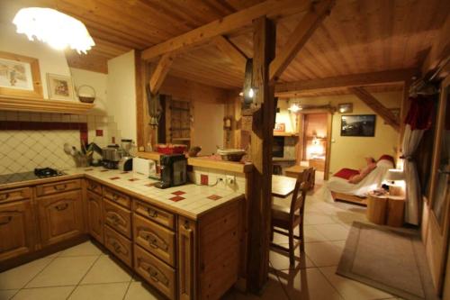 une cuisine avec des placards en bois et un salon dans l'établissement appartement cozy dans chalet 6 pers voiture 4 roues motrice a dispo, à La Clusaz