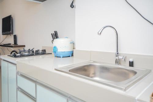 a kitchen counter with a sink and a mixer at Elegant Studio Parkland Avenue Apartment By Travelio in Babakan