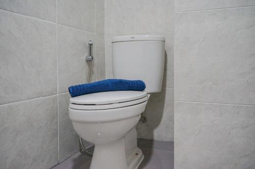 a bathroom with a toilet with a blue towel on it at Elegant Studio Parkland Avenue Apartment By Travelio in Babakan