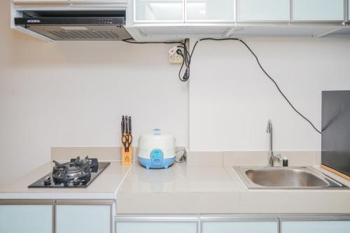 a kitchen with a sink and a stove top oven at Elegant Studio Parkland Avenue Apartment By Travelio in Babakan