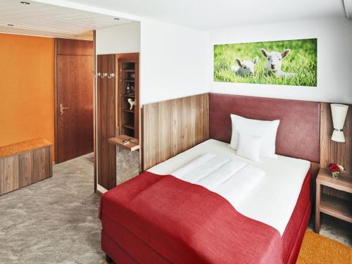 a bedroom with a large bed with a red blanket at Hotel Lamm in Ostfildern
