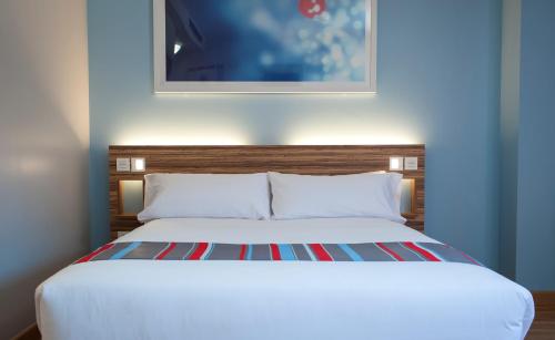 a bedroom with a white bed with a painting above it at Travelodge Barcelona Poblenou in Barcelona