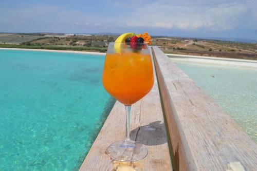 una bebida sentada en una mesa junto a una piscina en Kapuhala Sicily en Marzamemi