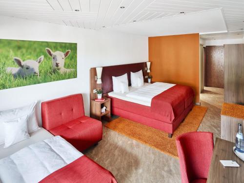 a hotel room with two beds and red chairs at Hotel Lamm in Ostfildern