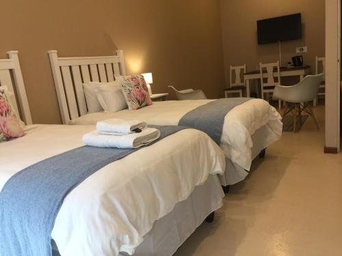 two beds in a hotel room with towels on them at The Vine in Klawer