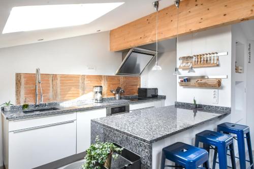 une cuisine avec des placards blancs et des tabourets bleus dans l'établissement NOCNOC - Le Mosaïque, centre Toulouse, à Toulouse