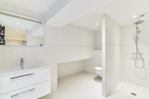 La salle de bains blanche est pourvue d'une douche et de toilettes. dans l'établissement High Standing Comfortable Loft 125m2 city center, à Strasbourg