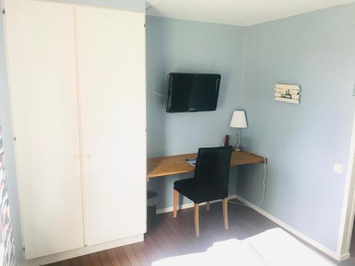 a room with a desk with a tv and a chair at Wisingsö Hotell in Visingsö