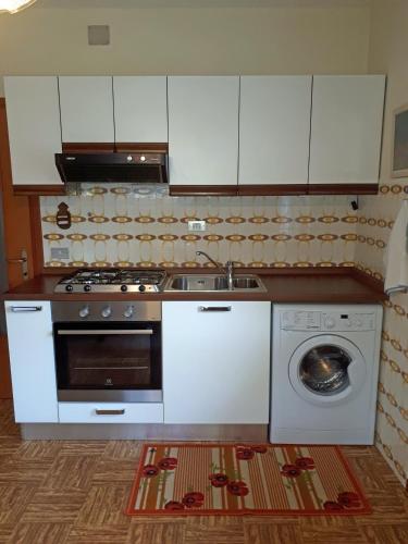 a kitchen with a stove and a washing machine at Appartamento Mariuccia in Dosoledo