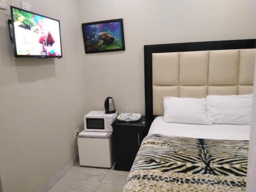 um quarto de hotel com uma cama e uma televisão na parede em Classic-Lodge em Kempton Park