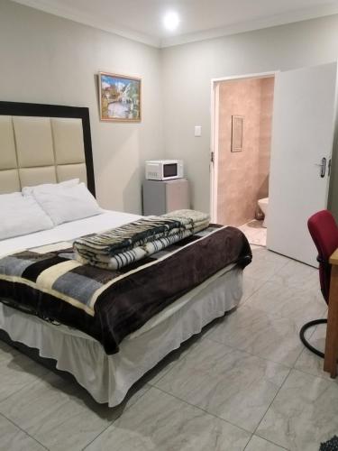 a bedroom with a large bed and a microwave at Classic-Lodge in Kempton Park