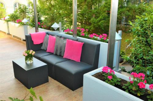 a black couch with pink pillows on a patio at Hotel Admiral am Kurpark in Baden