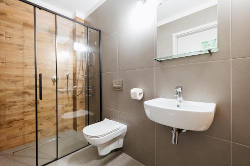 a bathroom with a toilet, sink, and shower stall at Hotel Horeka in Ełk