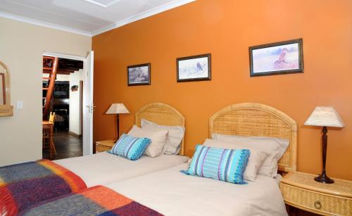 two beds in a room with orange walls at Stonecutters Lodge in Dullstroom